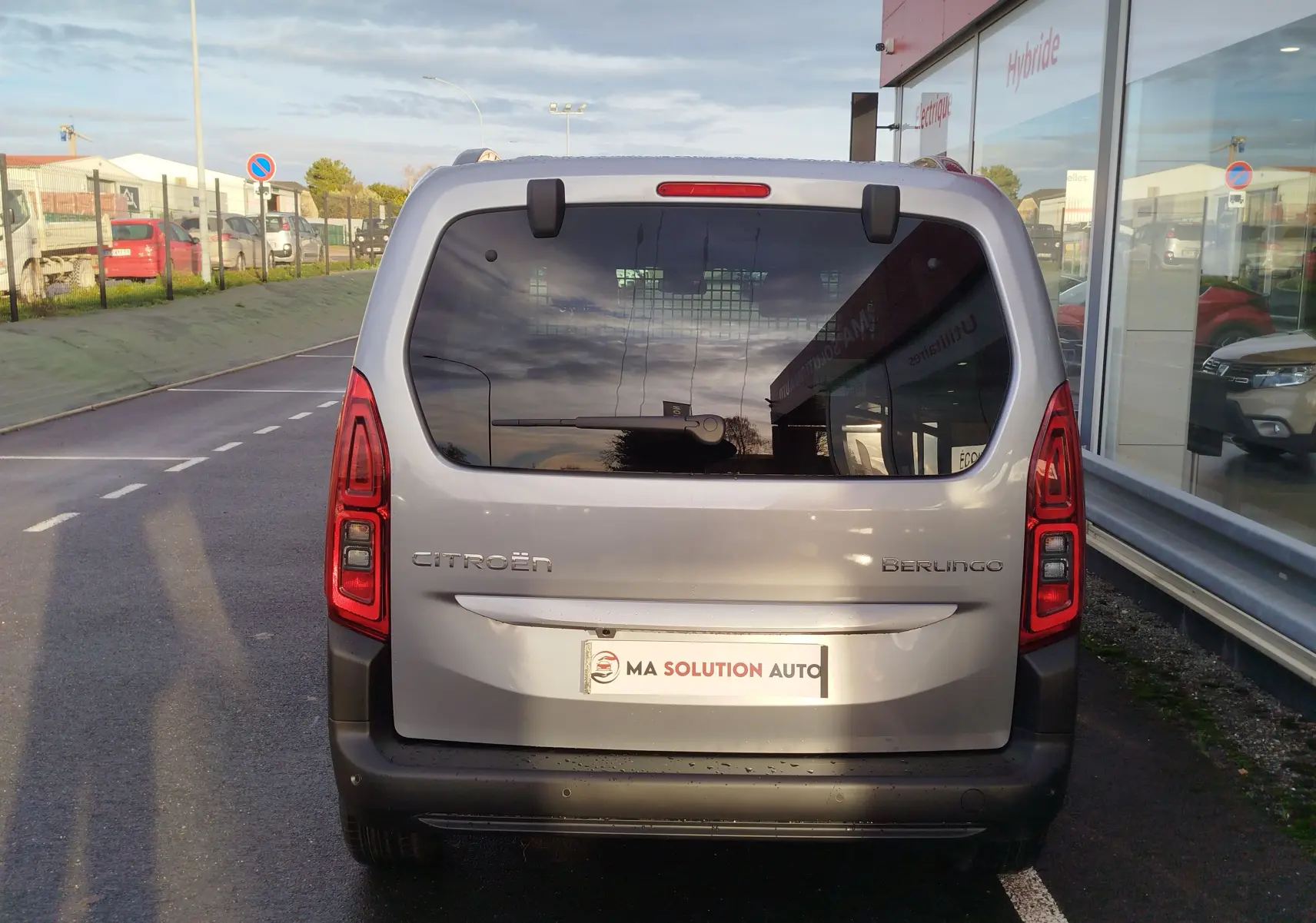 Vue arrière d'un Citroën Berlingo gris acier 2025 avec vitres teintées et feux arrière rouges allumés.