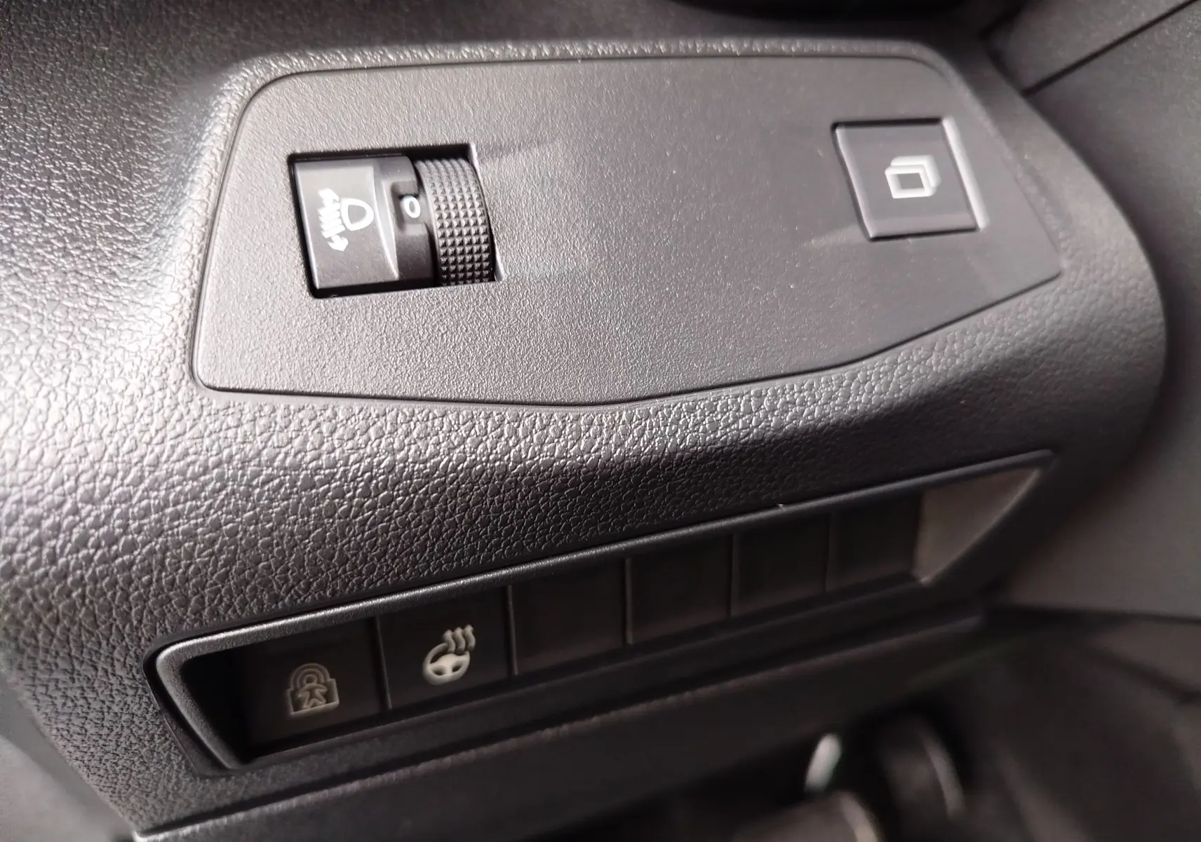 Détail intérieur des commandes noires sur tableau de bord texturé du Citroën Berlingo 2025, version essence gris acier.