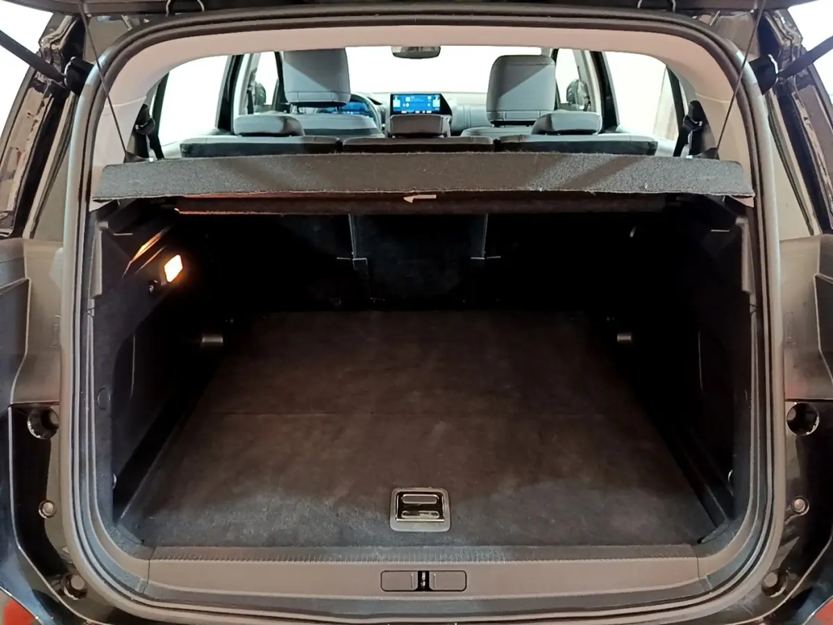 Vue arrière du coffre ouvert d’un Citroën C5 Aircross hybride rechargeable noir, montrant l’espace de chargement vide et la tablette cache-bagages.