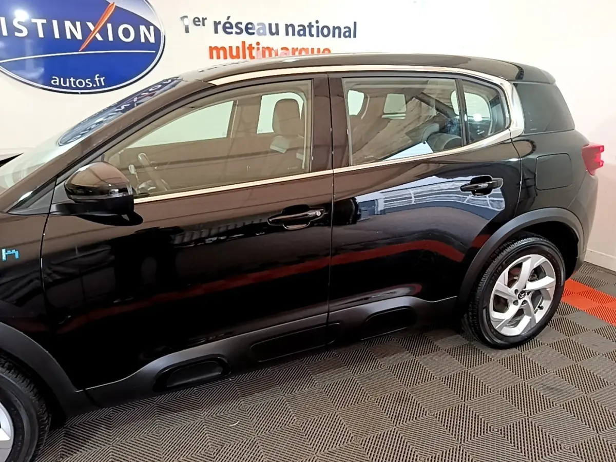 Vue latérale côté gauche d'un Citroën C5 Aircross hybride rechargeable noir brillant en intérieur showroom.
