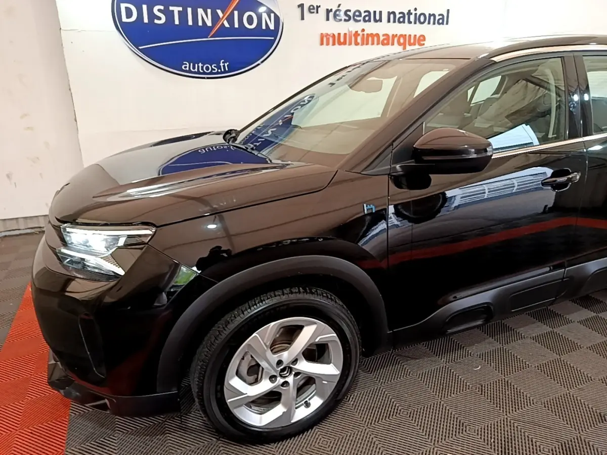 Vue 3/4 avant côté gauche d’un Citroën C5 Aircross hybride rechargeable noir brillant avec jantes argentées.