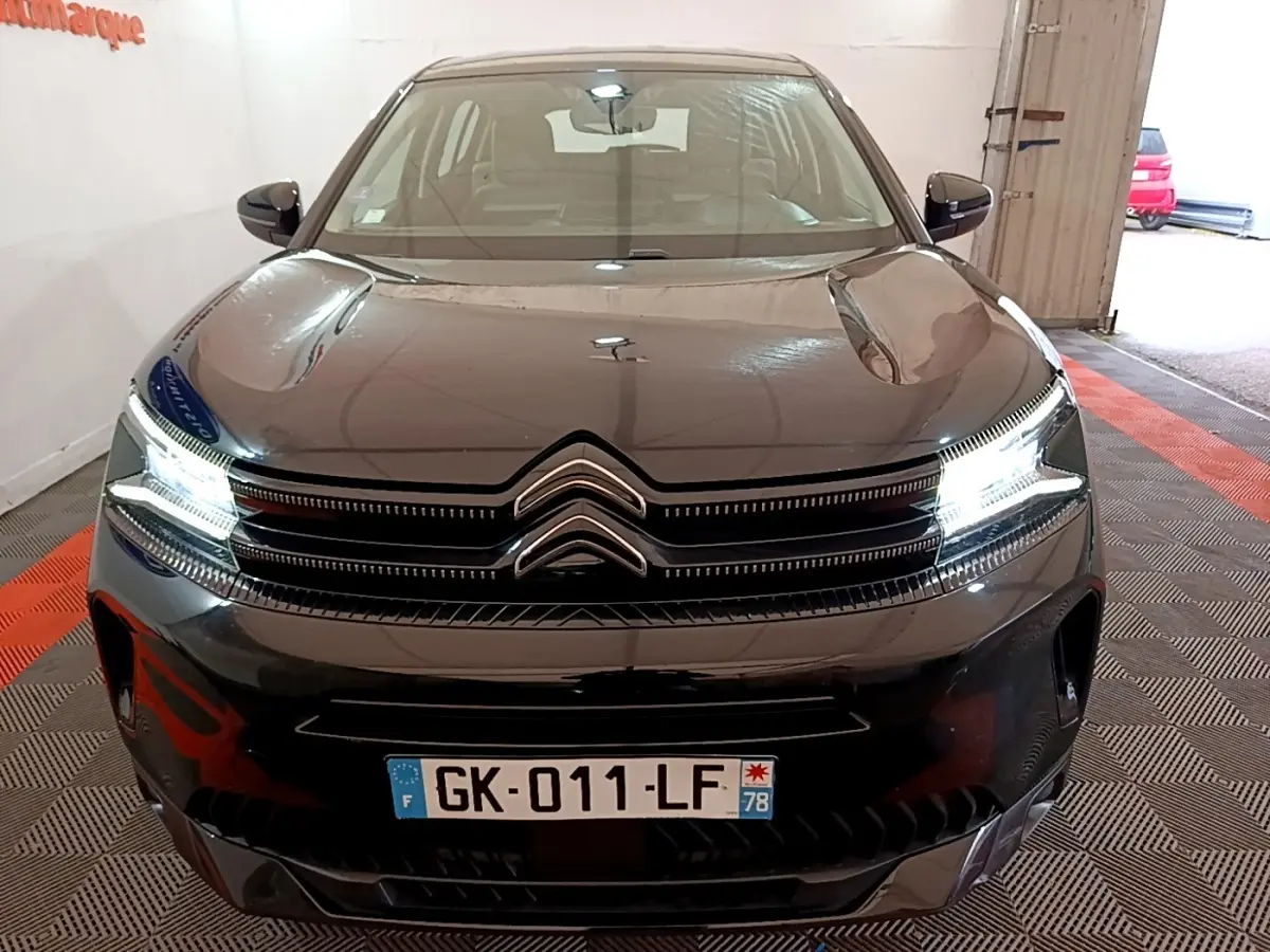 Vue avant d'une Citroën C5 Aircross hybride rechargeable noire avec phares LED allumés en intérieur.
