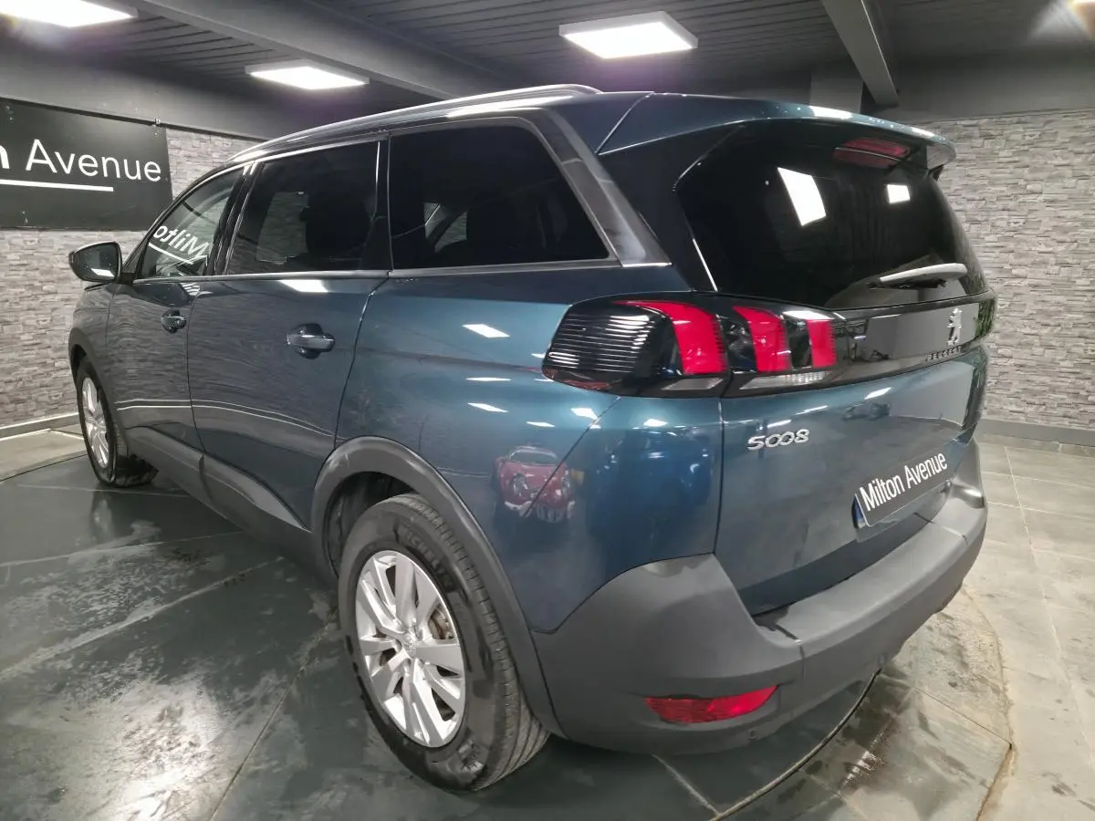 Vue 3/4 arrière droite du Peugeot 5008 bleu métallisé avec feux arrière à griffes et jantes alliage 17 pouces.