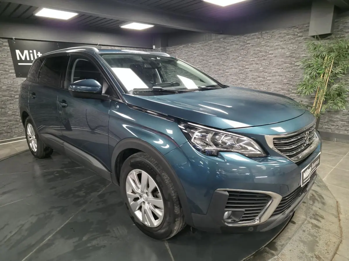 Peugeot 5008 bleu métallisé vue 3/4 avant droit avec calandre chromée et jantes alliage 17 pouces.