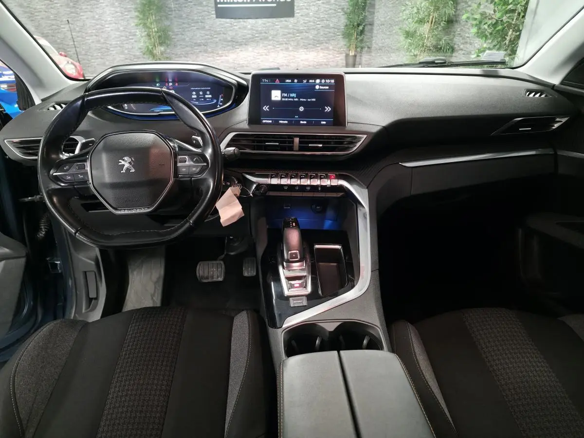 Intérieur du Peugeot 5008 bleu 2019 vu de face, tableau de bord moderne avec écran tactile et volant compact cuir.