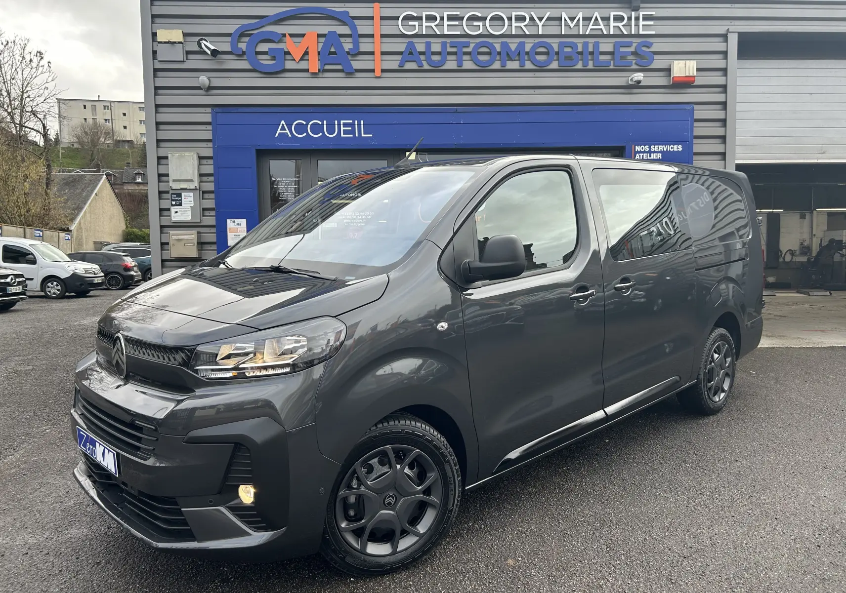 Vue 3/4 avant droit d’un Citroën Jumpy Cabine Approfondie gris titane métallisé garé devant un garage automobile.