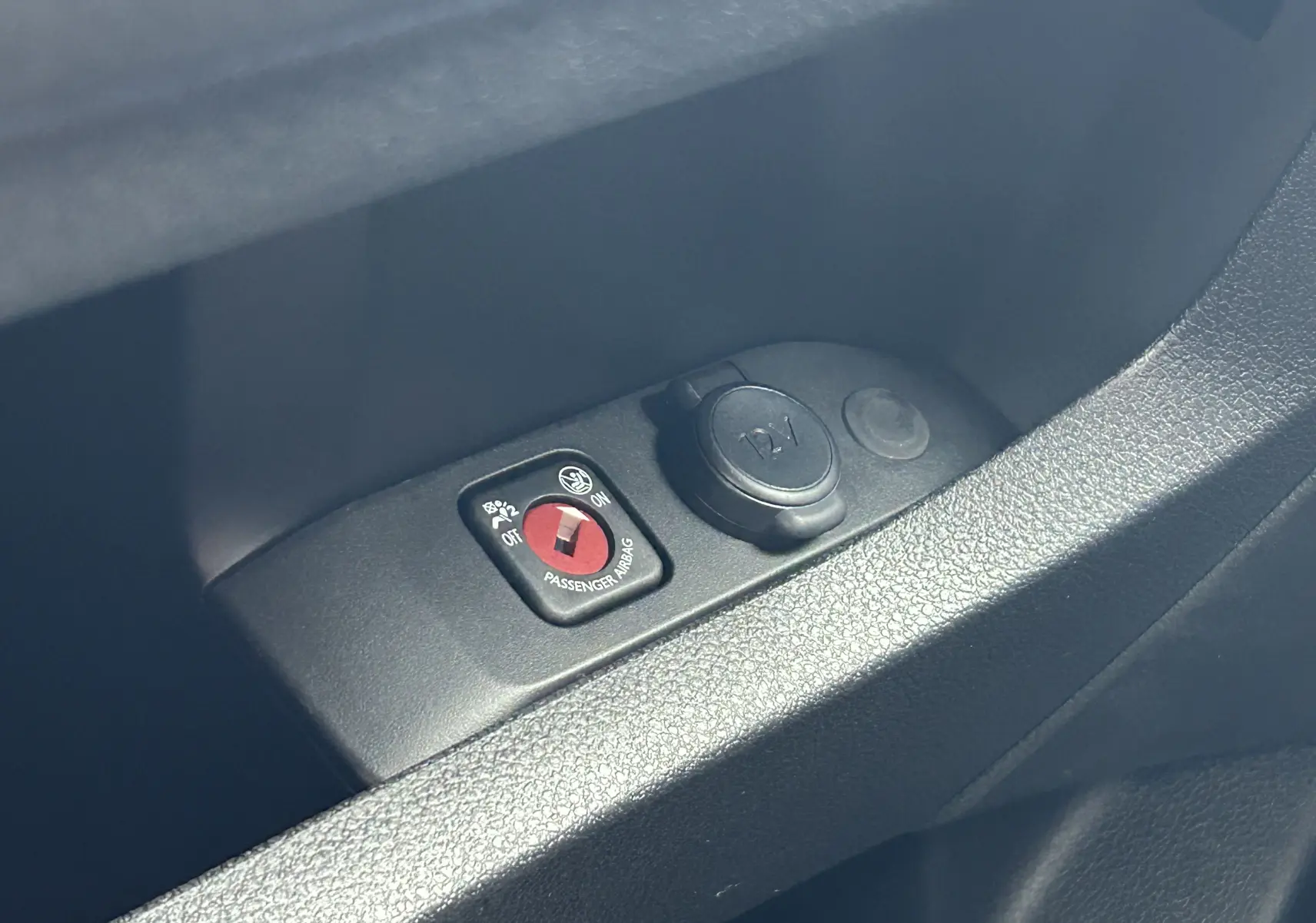 Gros plan sur le bouton de désactivation de l'airbag passager et prise 12V dans l'habitacle du Citroën Jumpy gris titane.