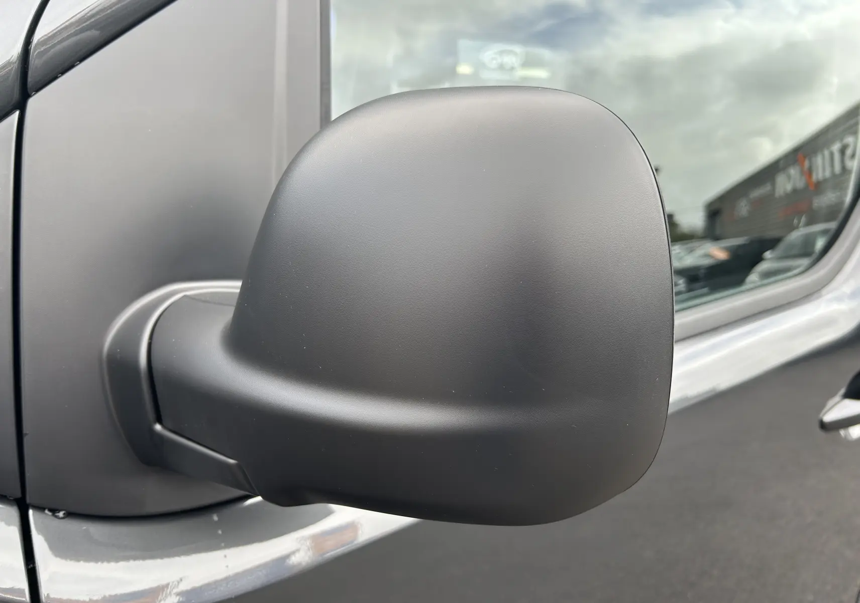 Rétroviseur latéral noir mat en gros plan sur la porte côté droit d’un Citroën Jumpy Cabine Approfondie gris titane.