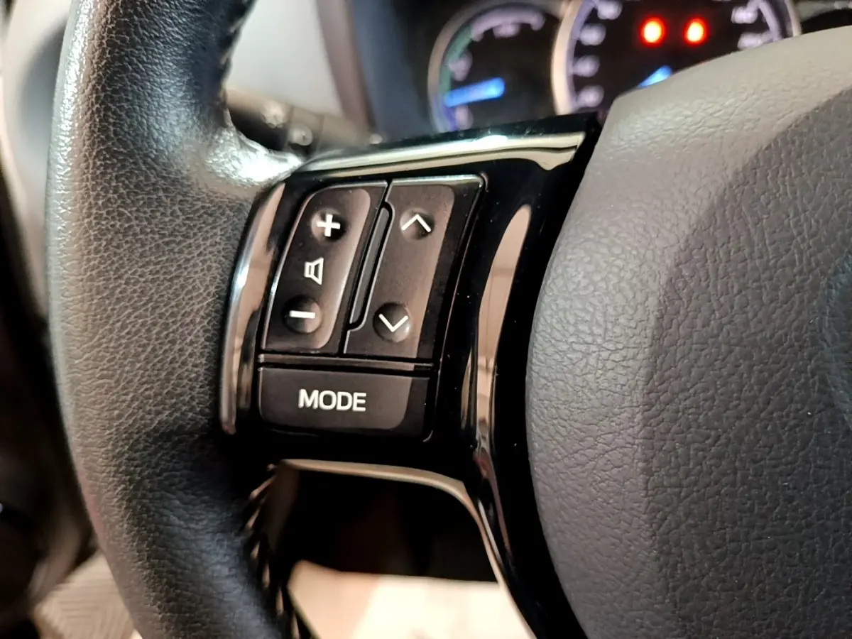 Gros plan sur le côté gauche du volant en cuir noir de la Toyota Yaris 2019 avec boutons de contrôle audio et mode.