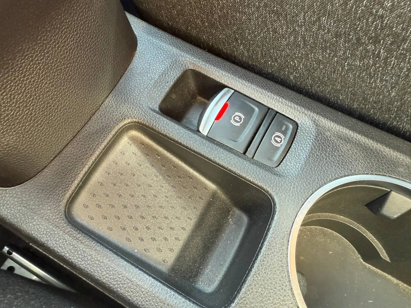 Gros plan sur la console centrale noire du Renault Captur 2025 avec frein à main électronique et rangement.