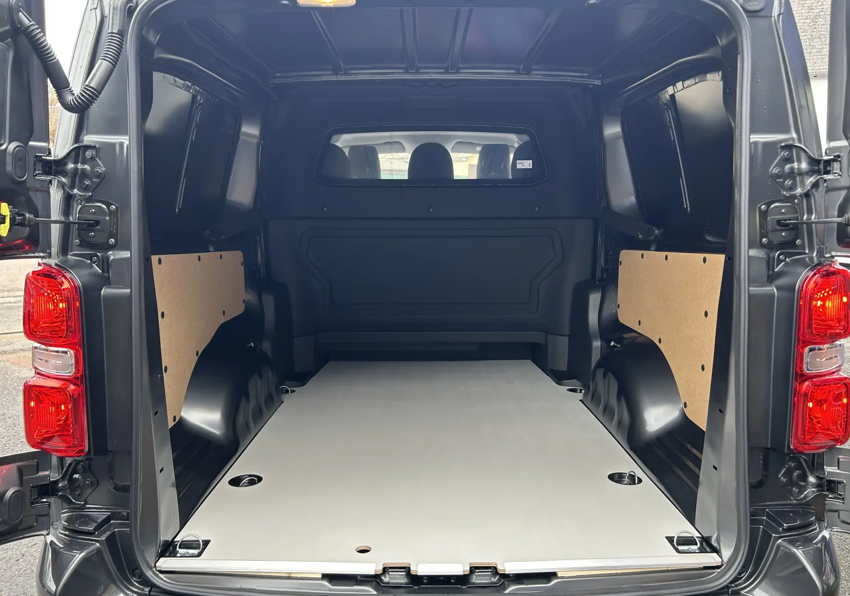 Vue arrière ouverte du Citroën Jumpy Long L3 gris titane métal, montrant l’espace de chargement vide et les panneaux latéraux en bois.