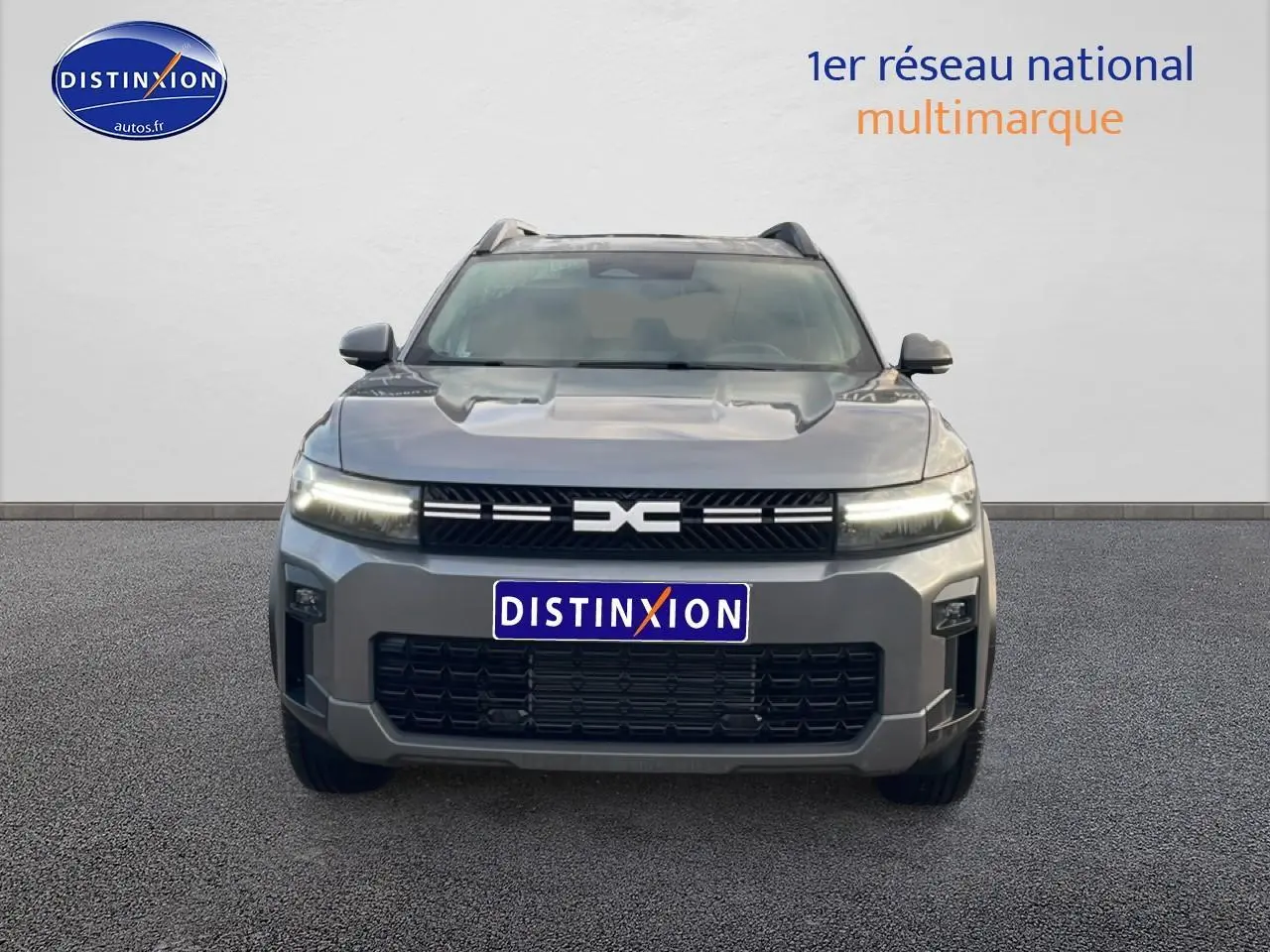 Vue frontale d'un Dacia Bigster gris schiste 2025 avec calandre noire et phares LED allumés.