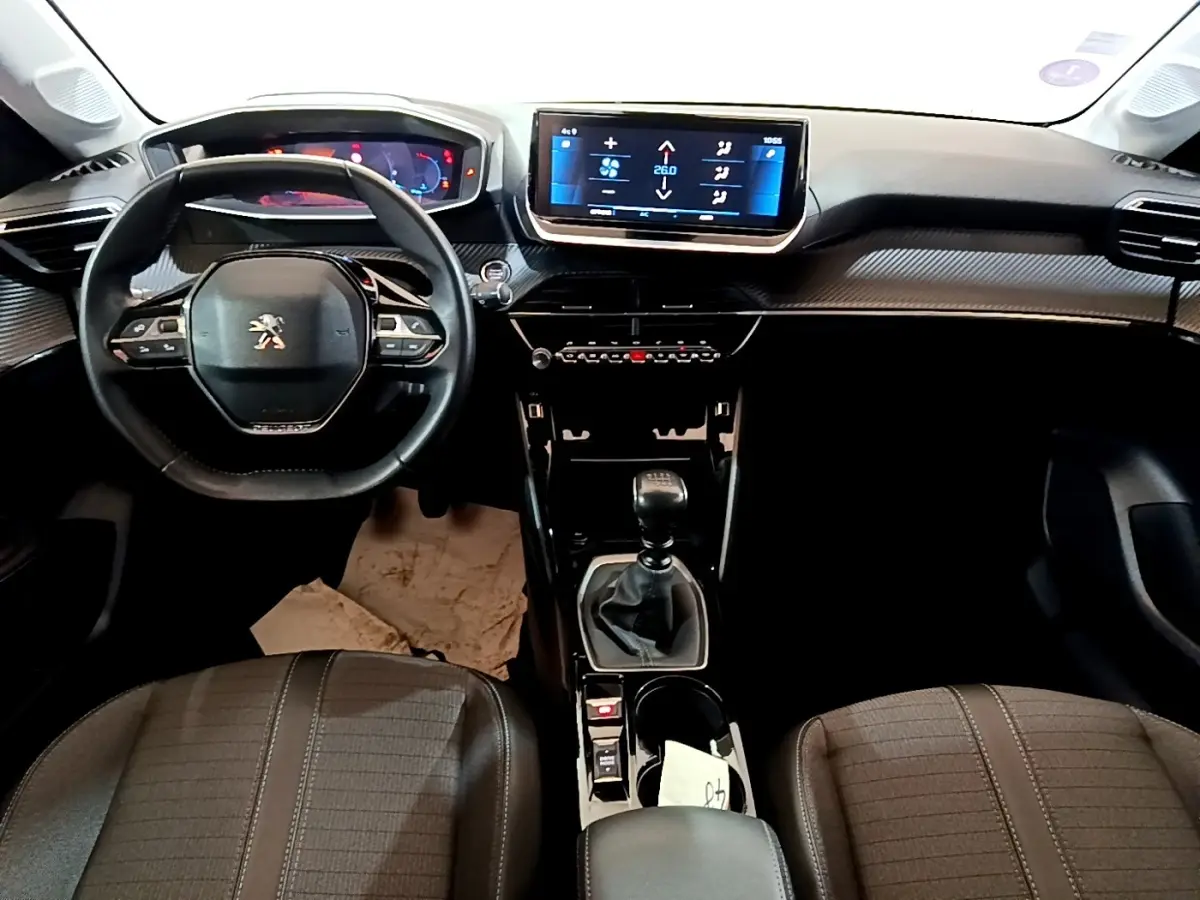 Vue intérieure avant de la Peugeot 208 PureTech 100 S&S Allure Business 2021, tableau de bord noir avec écran tactile central.
