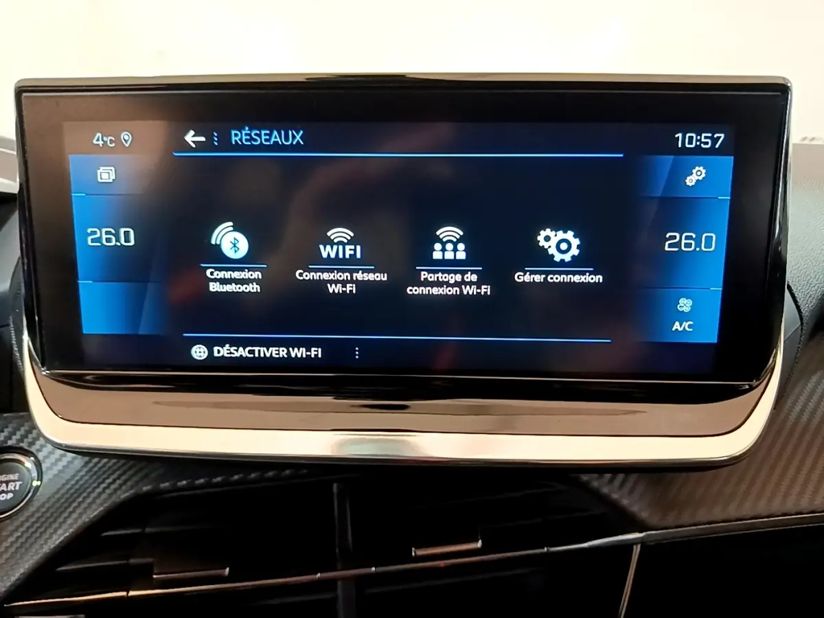 Écran tactile central 10 pouces du tableau de bord de la Peugeot 208 blanche, affichant les options réseau Wi-Fi et Bluetooth.