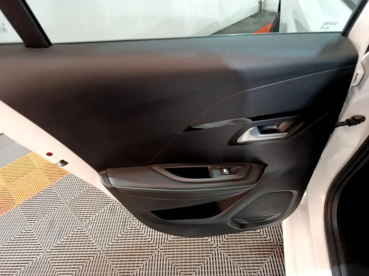 Vue rapprochée de la porte arrière droite blanche d'une Peugeot 208 2021 avec garniture intérieure noire et poignée argentée.