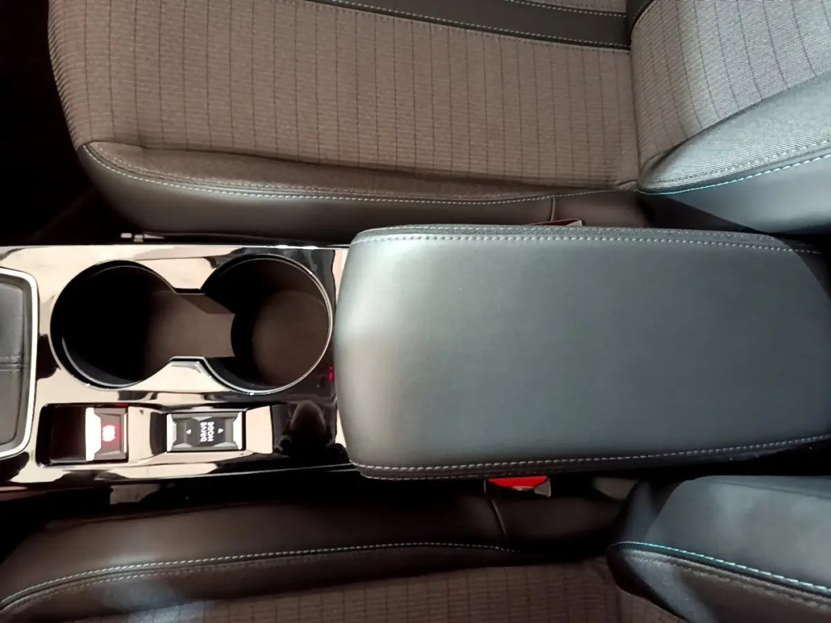 Vue rapprochée de l'accoudoir central noir et porte-gobelets de la Peugeot 208 PureTech 100 S&S Allure Business.