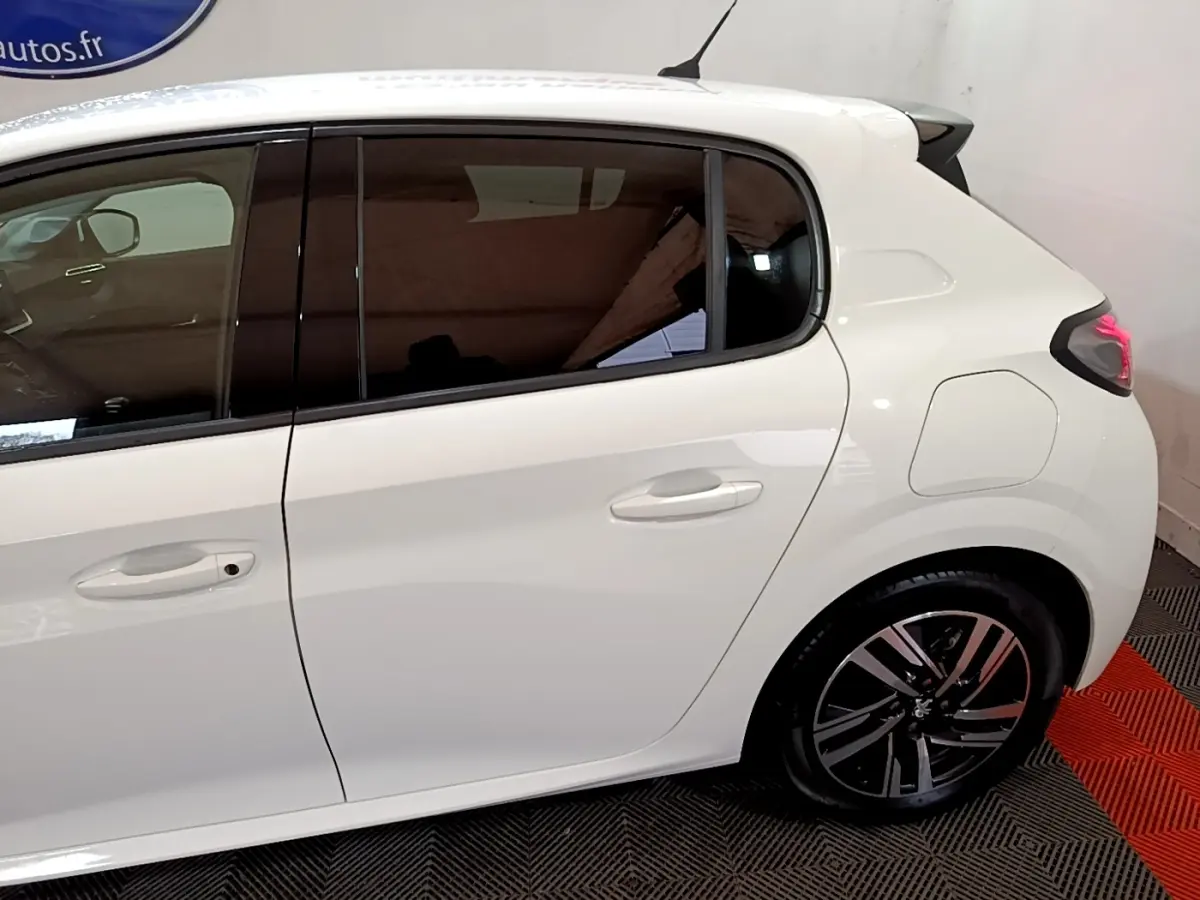 Vue latérale droite d'une Peugeot 208 blanche de 2021, avec vitres teintées et jantes alliage noires.