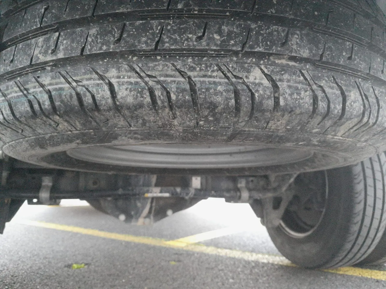 Gros plan sous le Renault Master blanc montrant la roue de secours et les roues jumelées arrière sur sol asphalté.