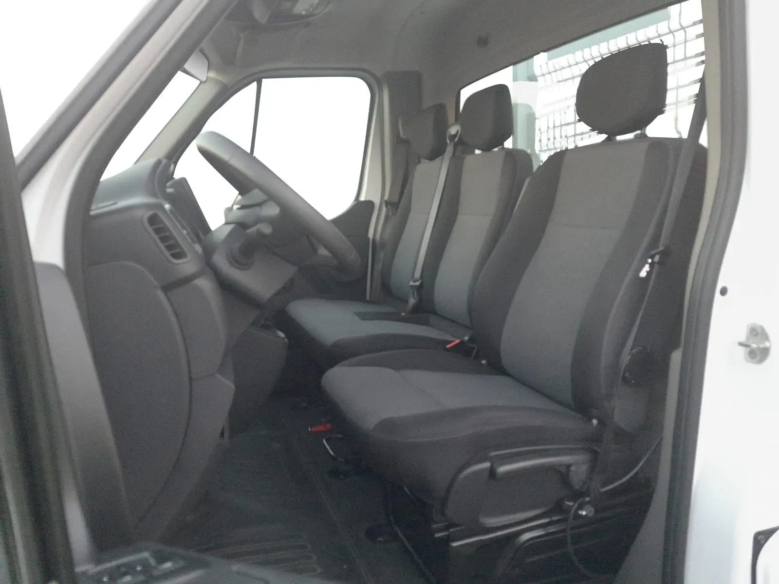 Vue intérieure côté conducteur du Renault Master Châssis Cabine blanc 2024, montrant les trois sièges en tissu gris et noir.