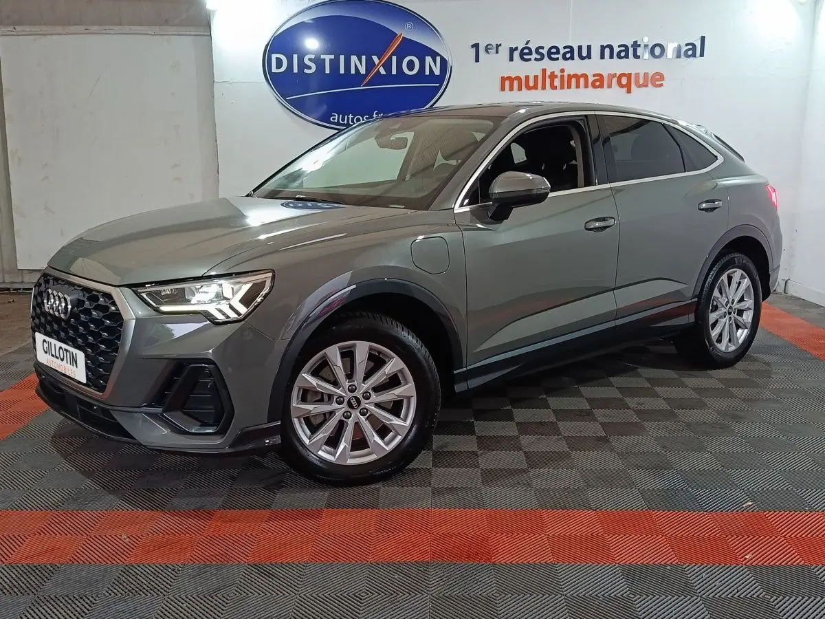 Audi Q3 Sportback gris foncé en 3/4 avant droit, avec calandre hexagonale et jantes alliage visibles.