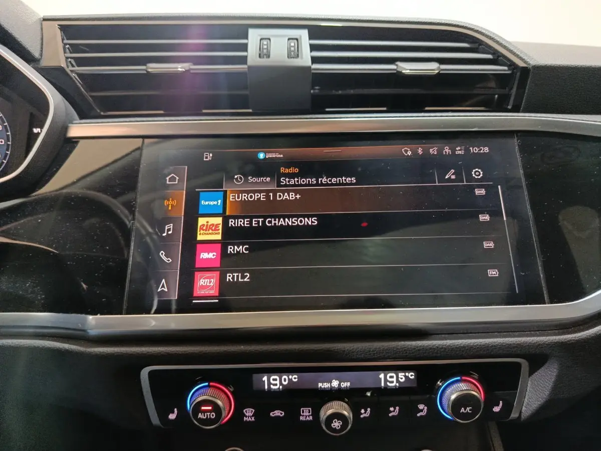 Écran tactile central et commandes climatisation bicolores dans l’habitacle d’un Audi Q3 Sportback gris foncé, vue frontale rapprochée.