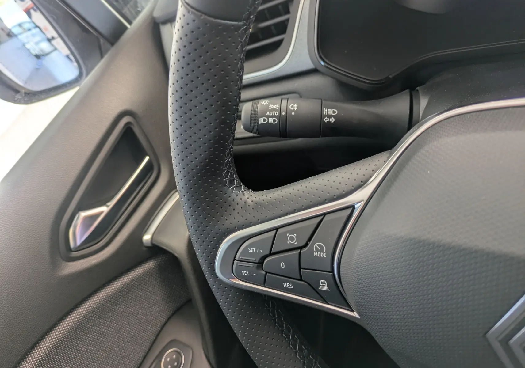 Gros plan sur le volant perforé côté gauche du Renault Captur gris Cassiopée 2025 avec commandes intégrées.