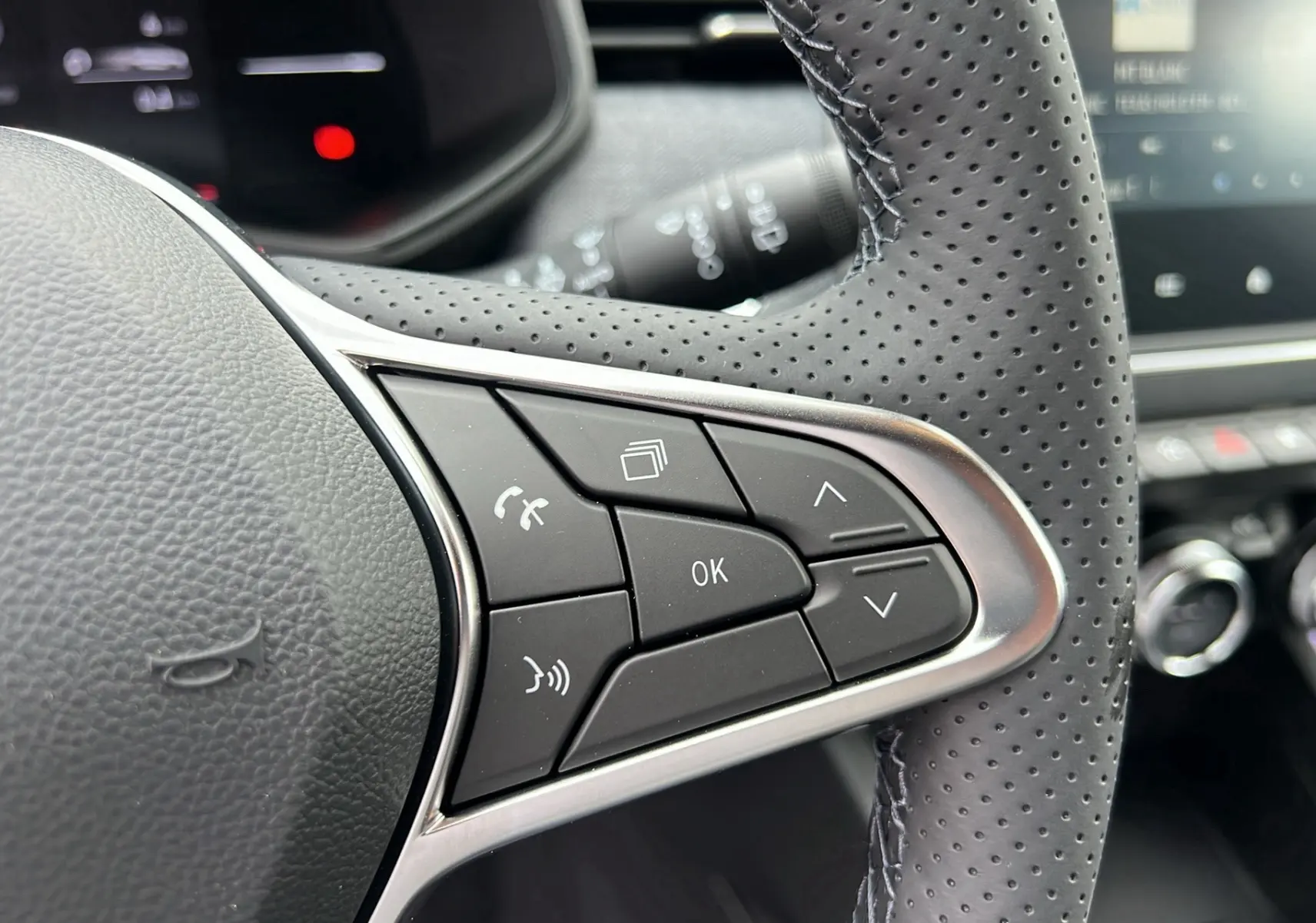 Gros plan sur les commandes au volant en cuir perforé du Renault Clio V TCE 90 Techno gris schiste, année 2025.