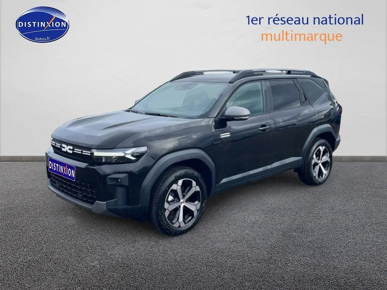 SUV Dacia Bigster noir en 3/4 avant droit, avec jantes alliage diamantées et barres de toit visibles.