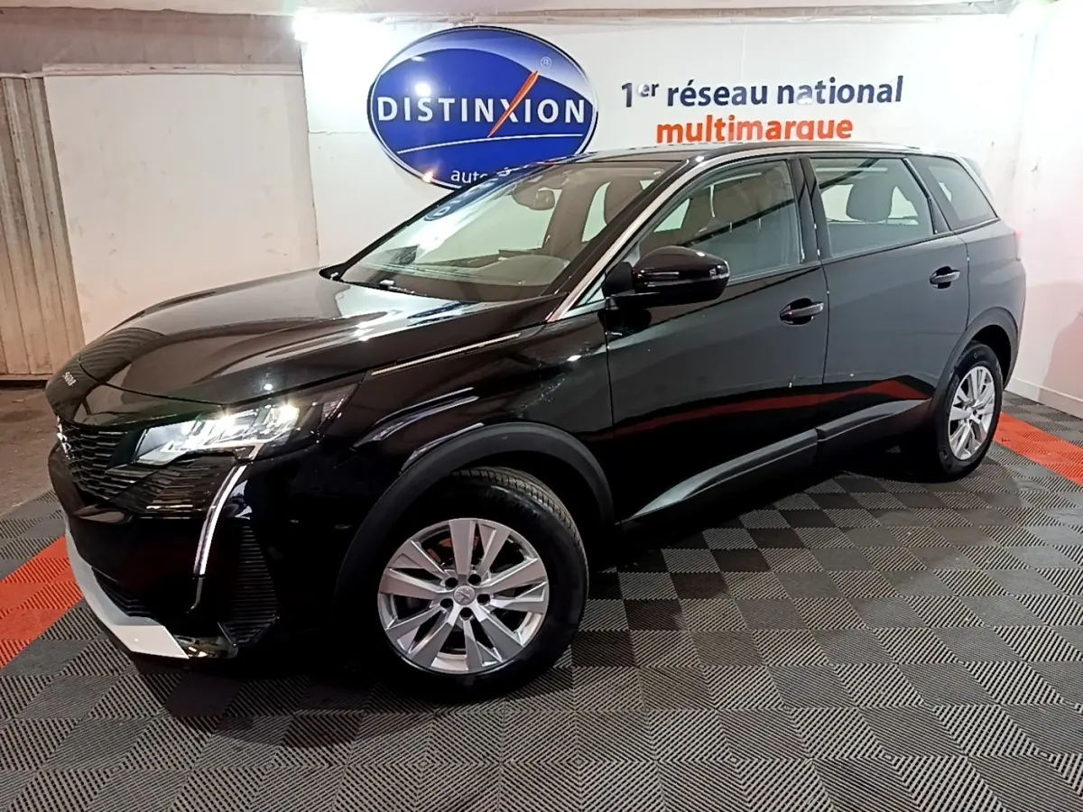 Peugeot 5008 noir vue 3/4 avant droit, avec feux LED et jantes alliage dans un showroom intérieur.