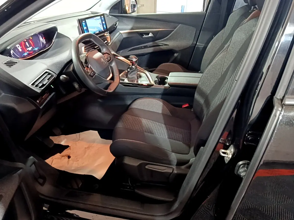 Vue intérieure côté conducteur du Peugeot 5008 noir, avec tableau de bord digital et écran tactile central visible.