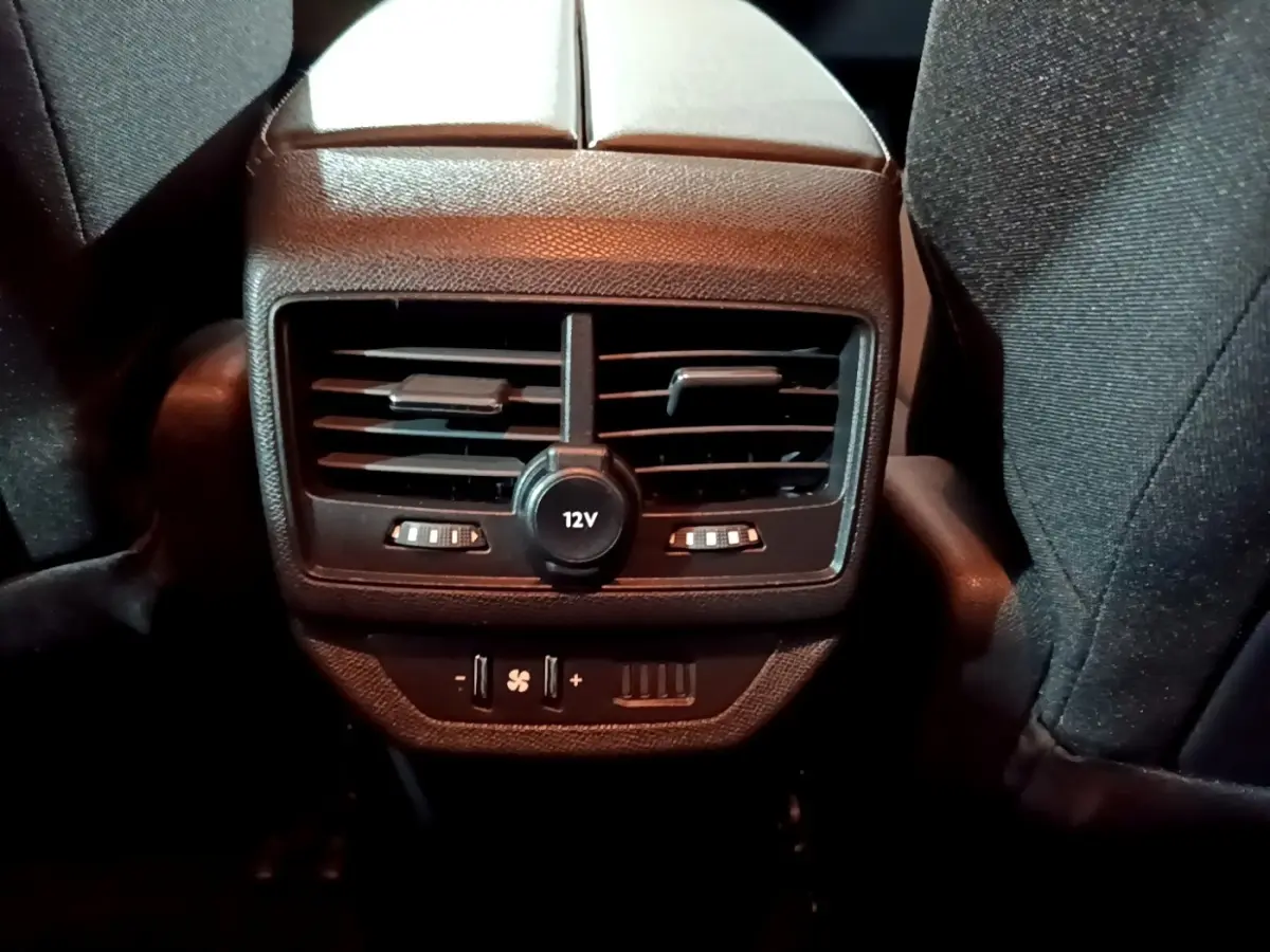 Vue rapprochée du panneau de ventilation arrière avec prise 12V et commandes de climatisation du Peugeot 5008 noir 2021.