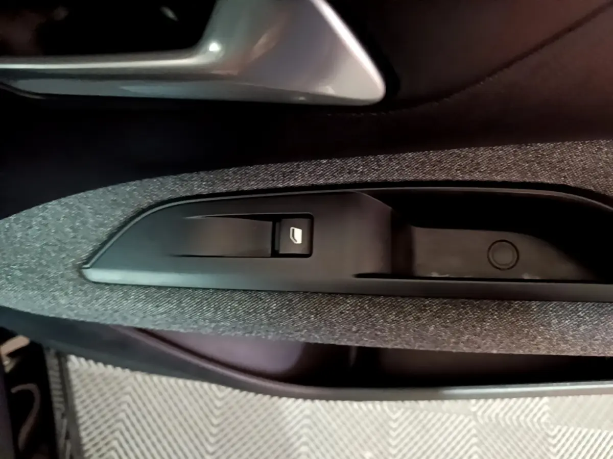 Gros plan sur la commande de lève-vitre côté conducteur du Peugeot 5008 noir, avec insert tissu gris foncé.