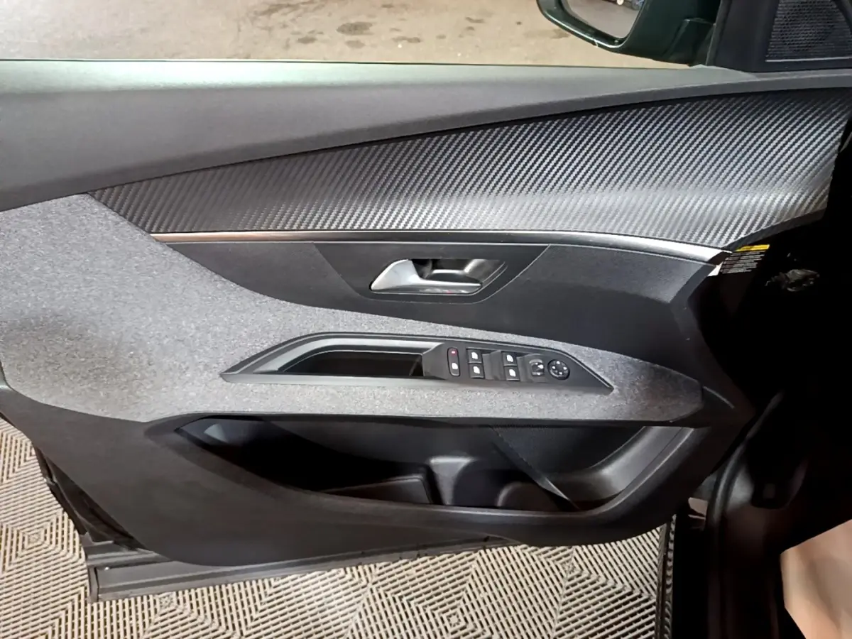 Gros plan sur la porte avant gauche noire du Peugeot 5008 2021, avec commandes des vitres et insert effet carbone.