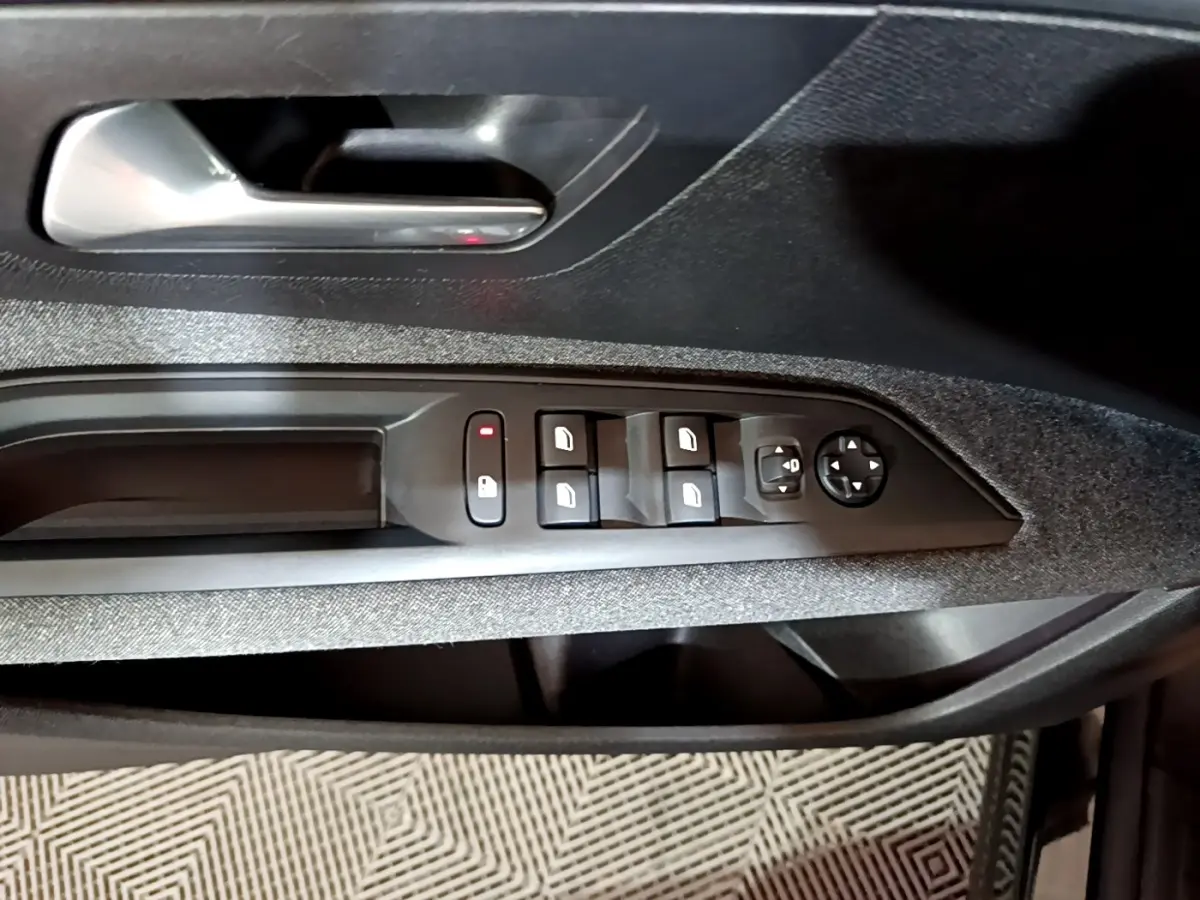 Vue rapprochée de la porte côté conducteur du Peugeot 5008 noir, montrant les commandes des vitres et rétroviseurs.