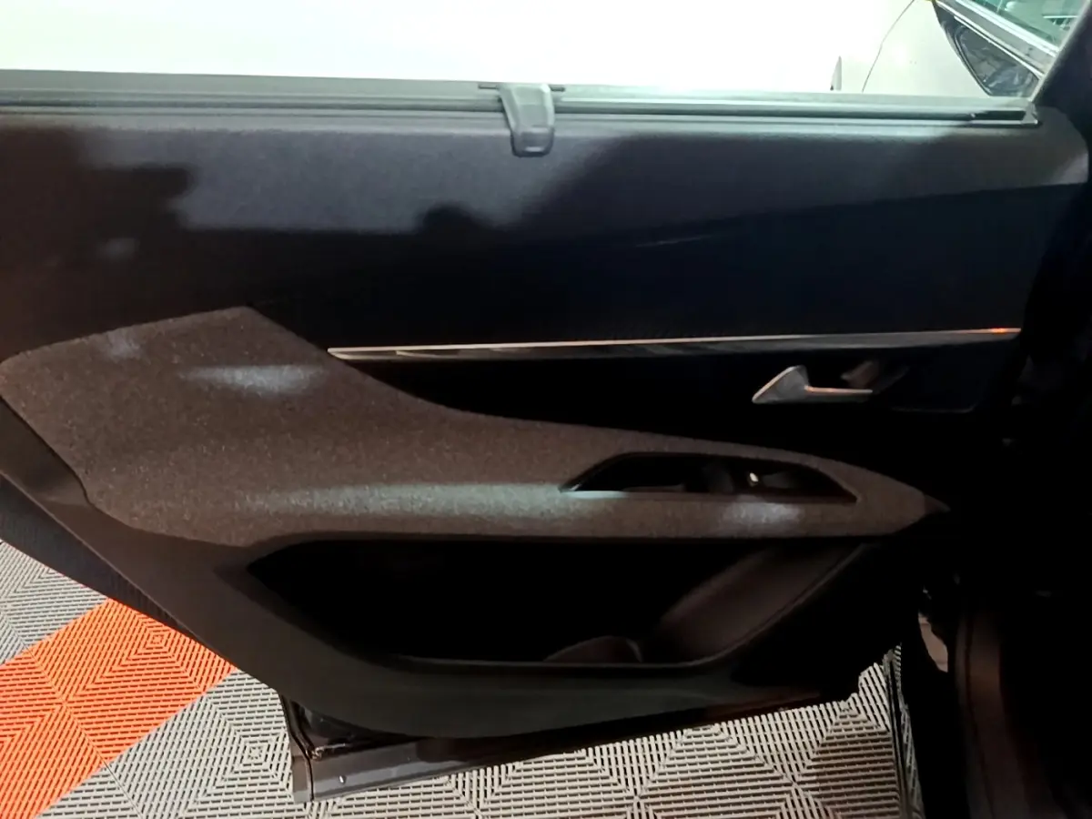 Vue intérieure du panneau de porte côté gauche du Peugeot 5008 noir, avec poignée argentée et commande de vitre intégrée.