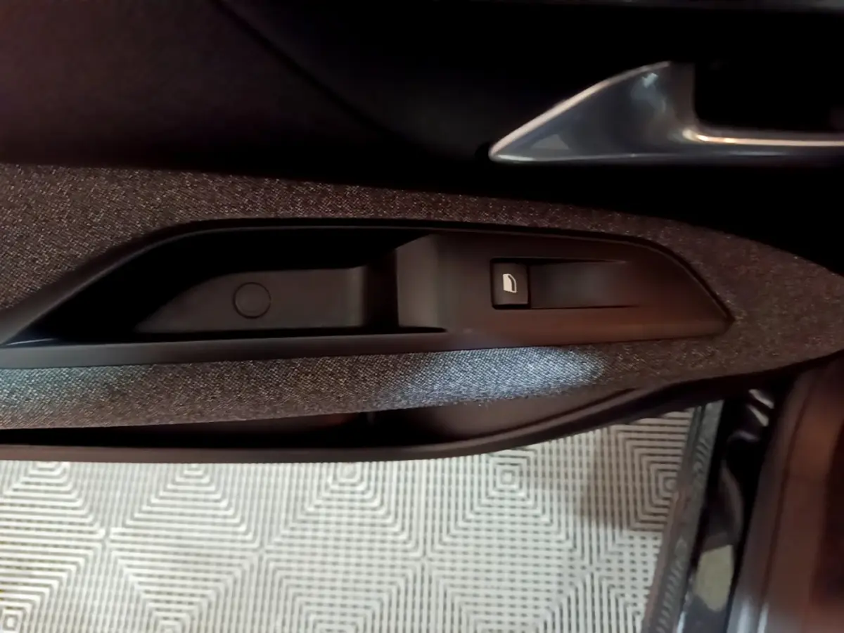 Détail de la commande de lève-vitre sur la porte côté conducteur d’un Peugeot 5008 noir, intérieur tissu gris.