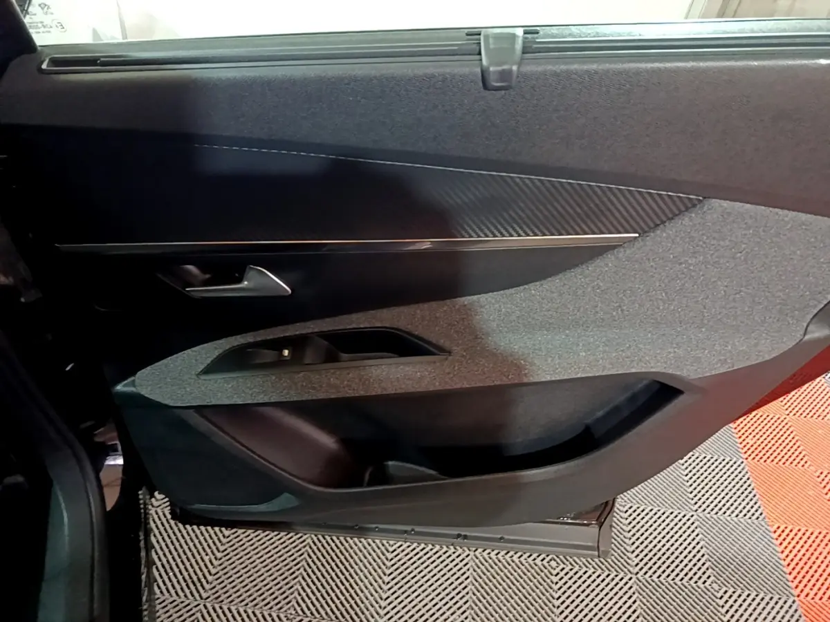 Vue rapprochée de la porte intérieure côté gauche du Peugeot 5008 noir, avec garniture tissu et insert effet carbone.