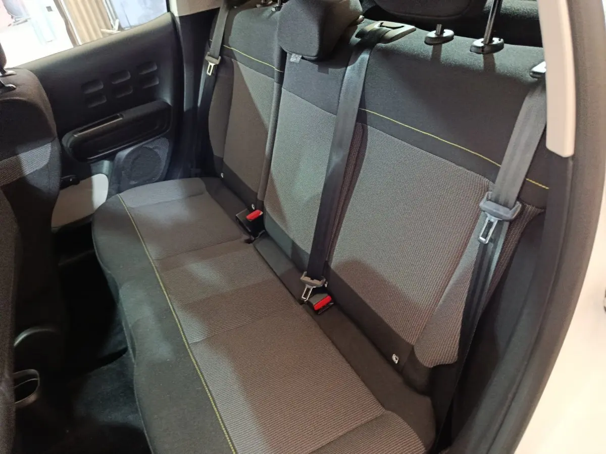 Vue intérieure de la banquette arrière grise avec surpiqûres jaunes de la Citroën C3 blanche, portes ouvertes côté droit.