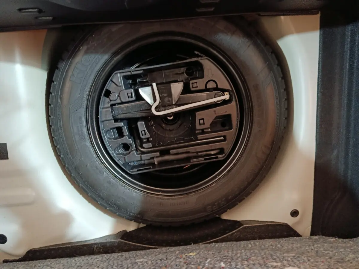 Vue rapprochée de la roue de secours noire dans le coffre blanc d'une Citroën C3 PureTech 2020.