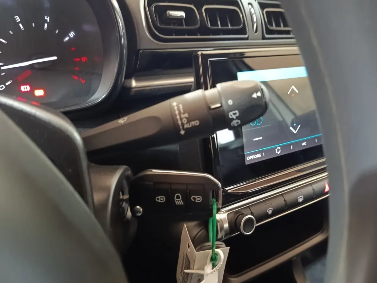Gros plan intérieur sur le tableau de bord et la clé insérée d'une Citroën C3 blanche, avec écran tactile allumé.