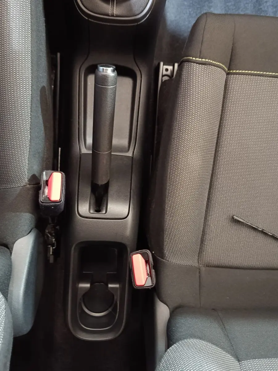 Vue plongeante sur la console centrale noire de la Citroën C3 avec frein à main manuel et sièges tissu gris foncé.