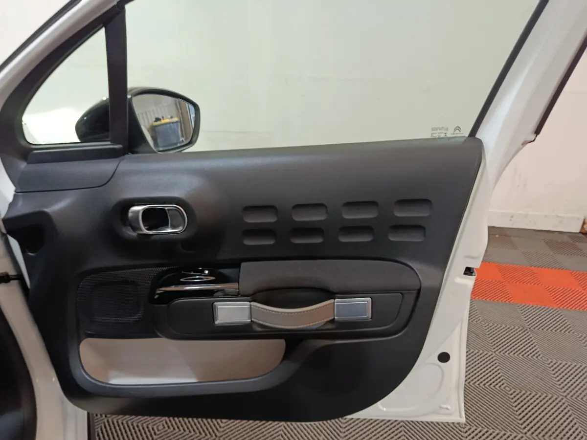 Vue intérieure de la porte avant gauche blanche de la Citroën C3 2020 avec poignée en cuir et inserts noirs.