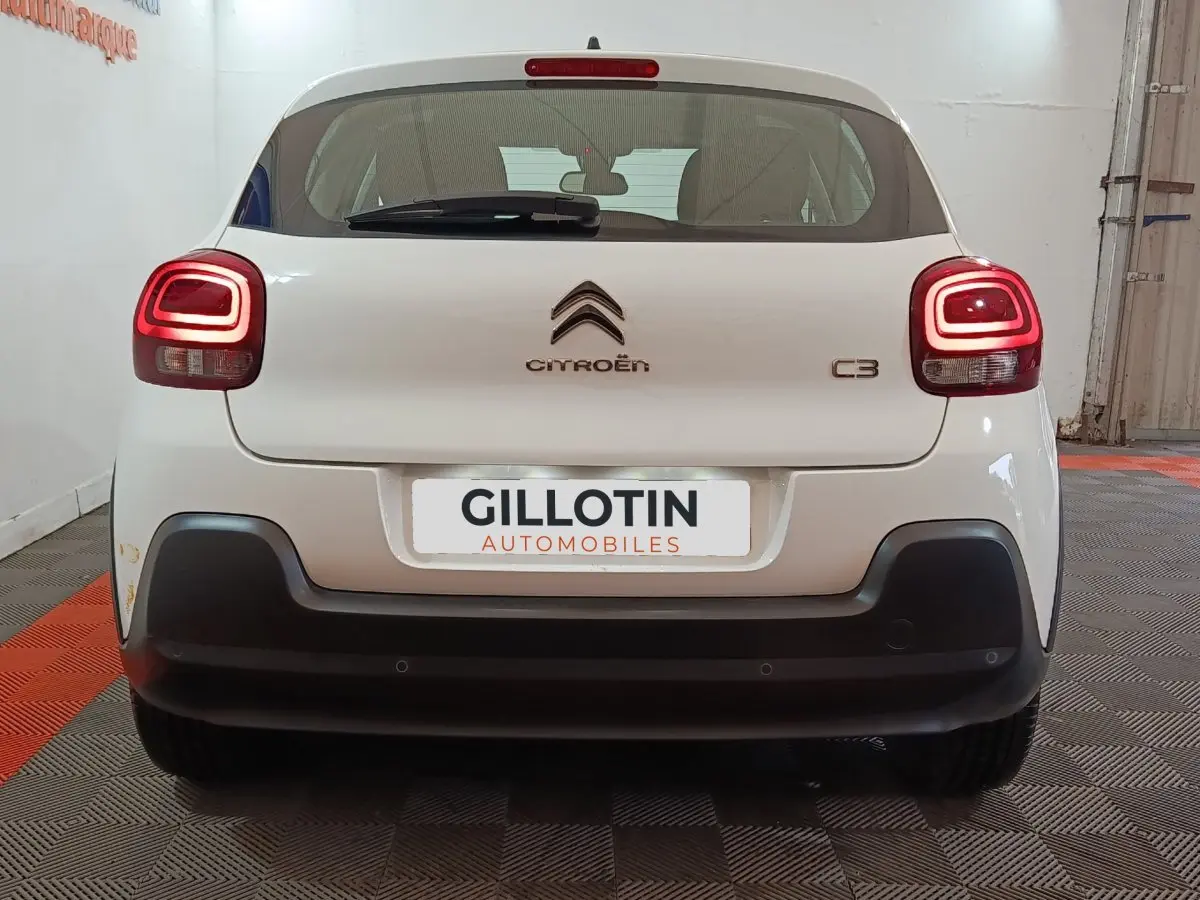 Vue arrière d'une Citroën C3 blanche de 2020 avec feux arrière allumés et pare-chocs noir contrastant.