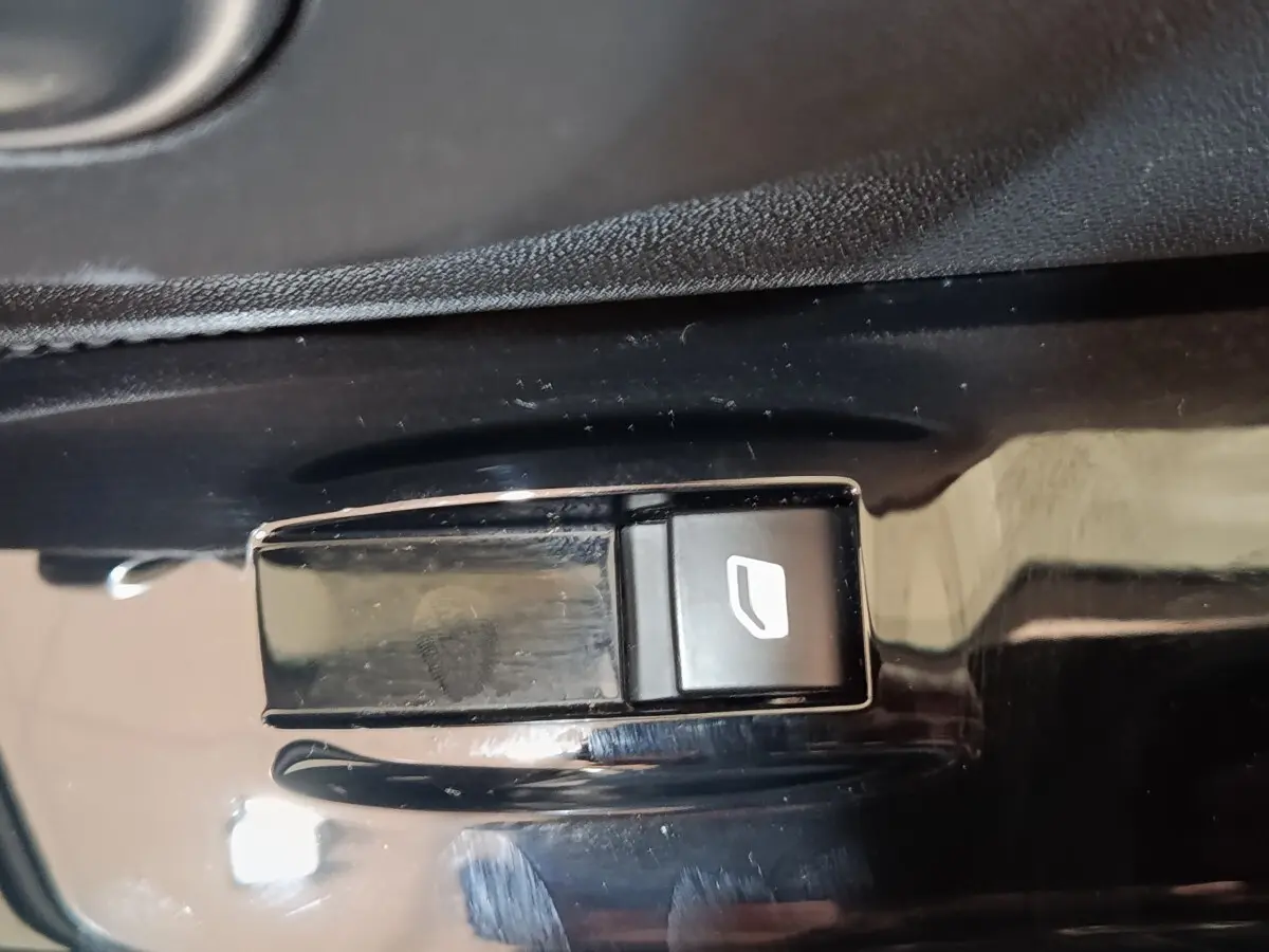 Gros plan sur le bouton de commande de lève-vitre côté conducteur de la Citroën C3 blanche, intérieur noir brillant.