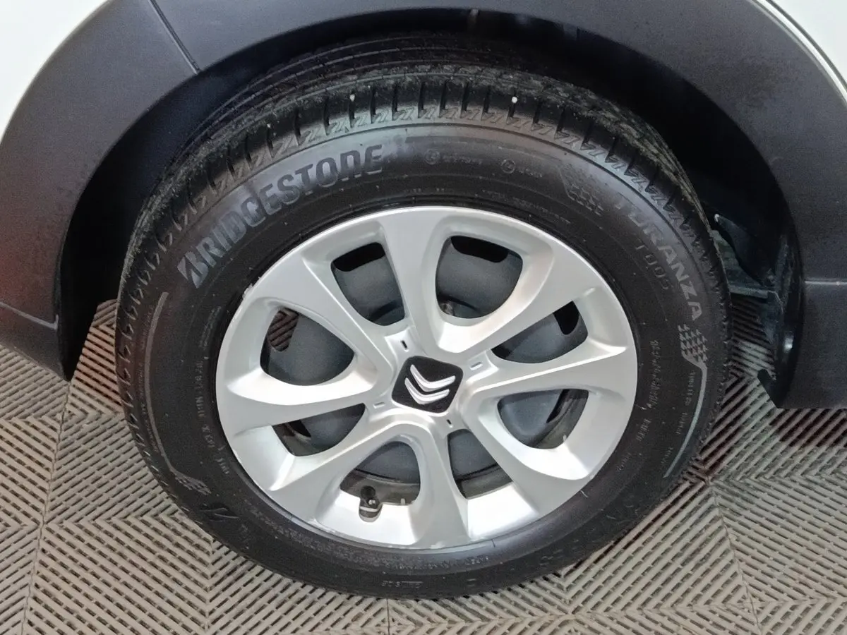 Gros plan sur la roue avant droite d'une Citroën C3 blanche avec jante alliage et logo Citroën central.