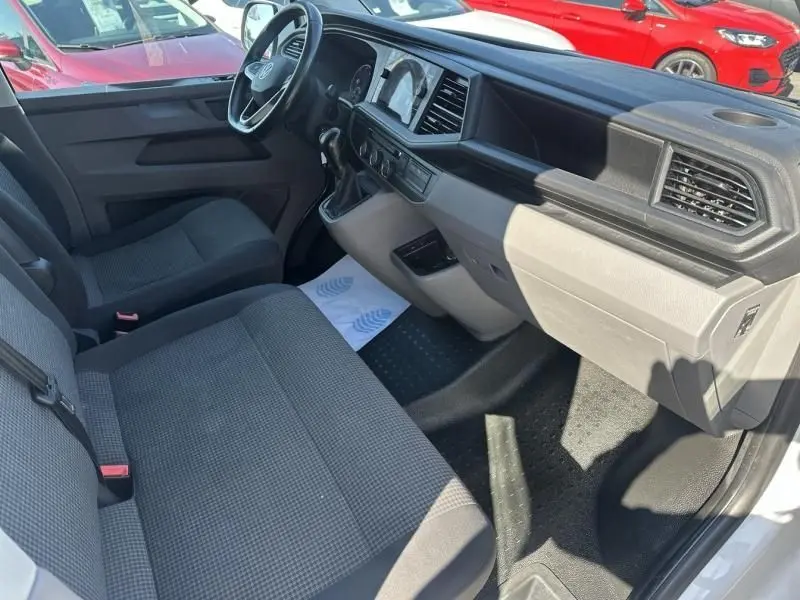 Intérieur avant droit du Volkswagen Transporter blanc 2022, montrant tableau de bord et sièges tissu gris.