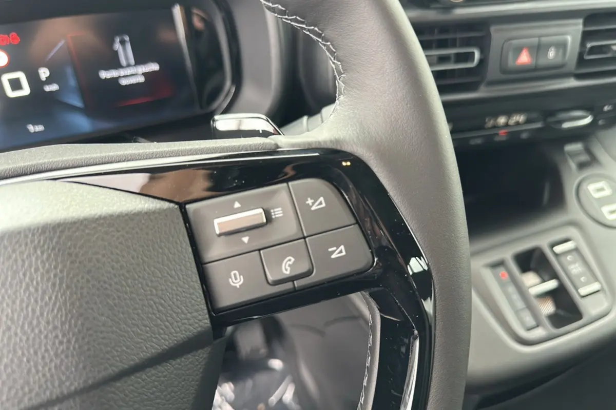 Gros plan sur les commandes au volant du Citroën Berlingo 2025, finition BlueHDi 130 EAT8, intérieur noir moderne.