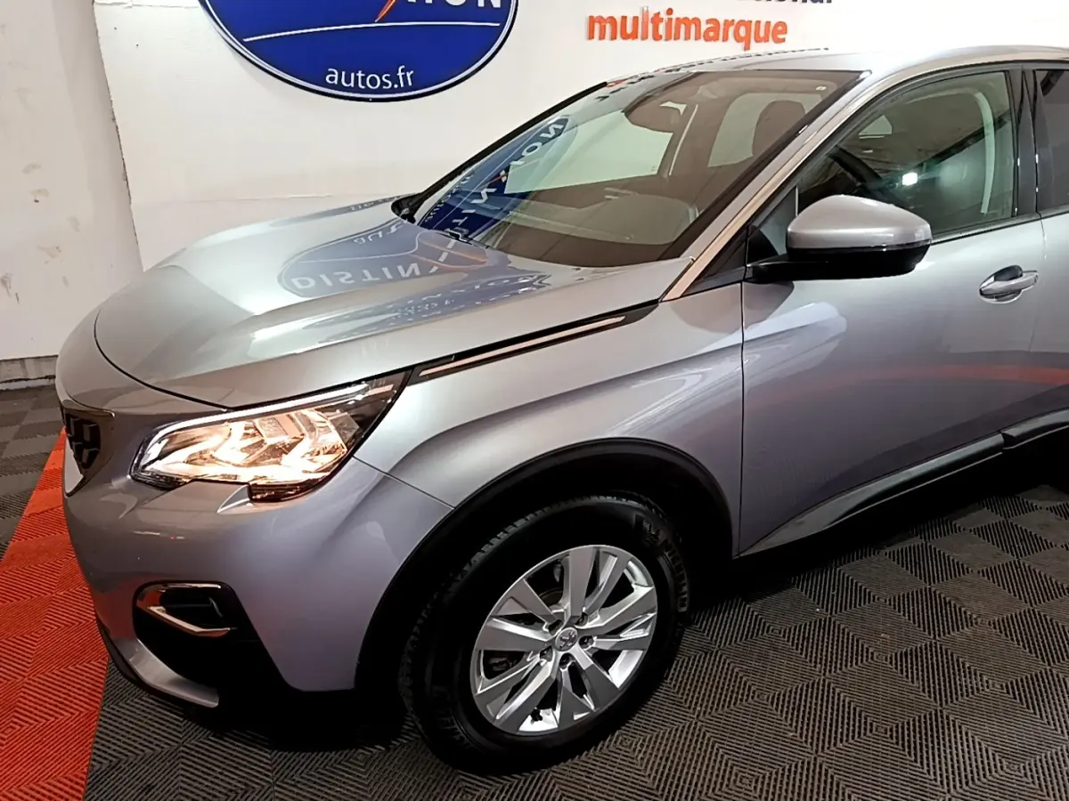 Vue 3/4 avant droit d’un Peugeot 3008 gris clair avec phares allumés et jantes alliage visibles.