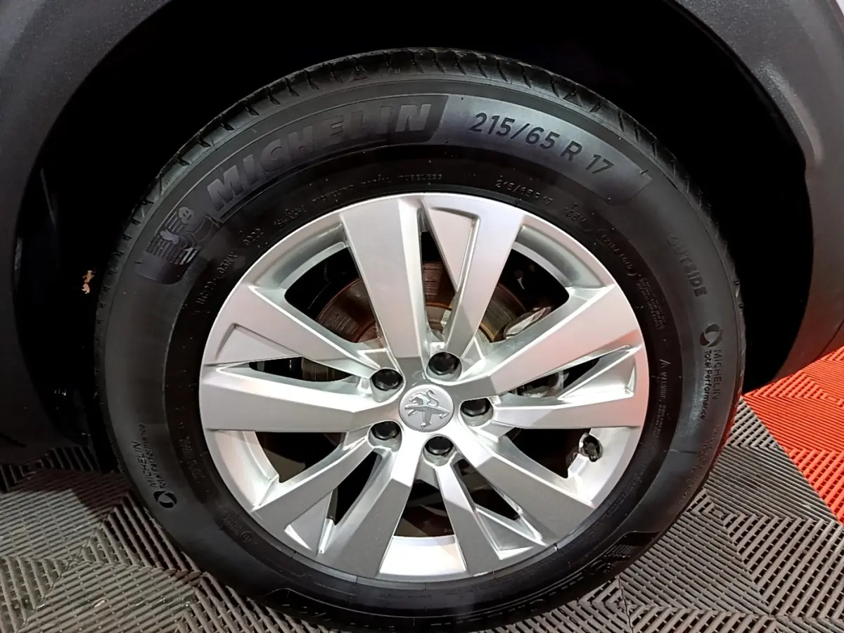 Gros plan sur la roue avant droite d’un Peugeot 3008 gris clair, jante alliage argent avec pneu Michelin.