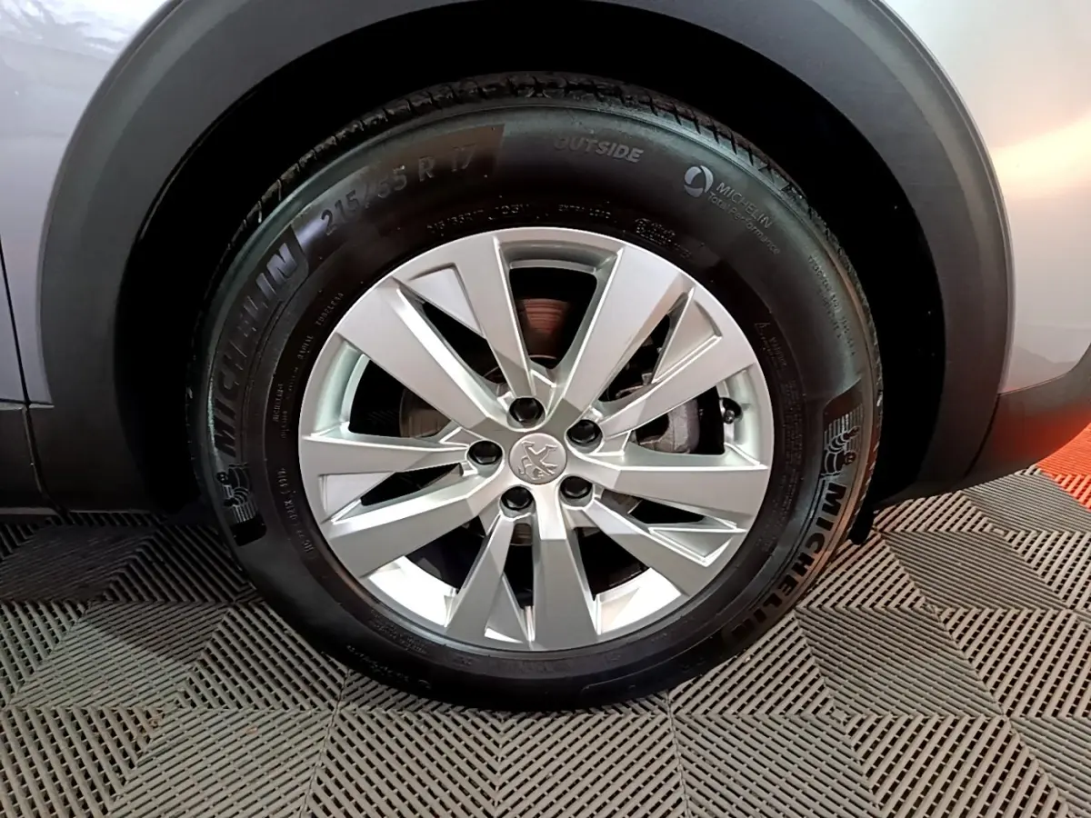 Gros plan sur la roue avant droite gris clair d’un Peugeot 3008 avec jante alliage et pneu Michelin.
